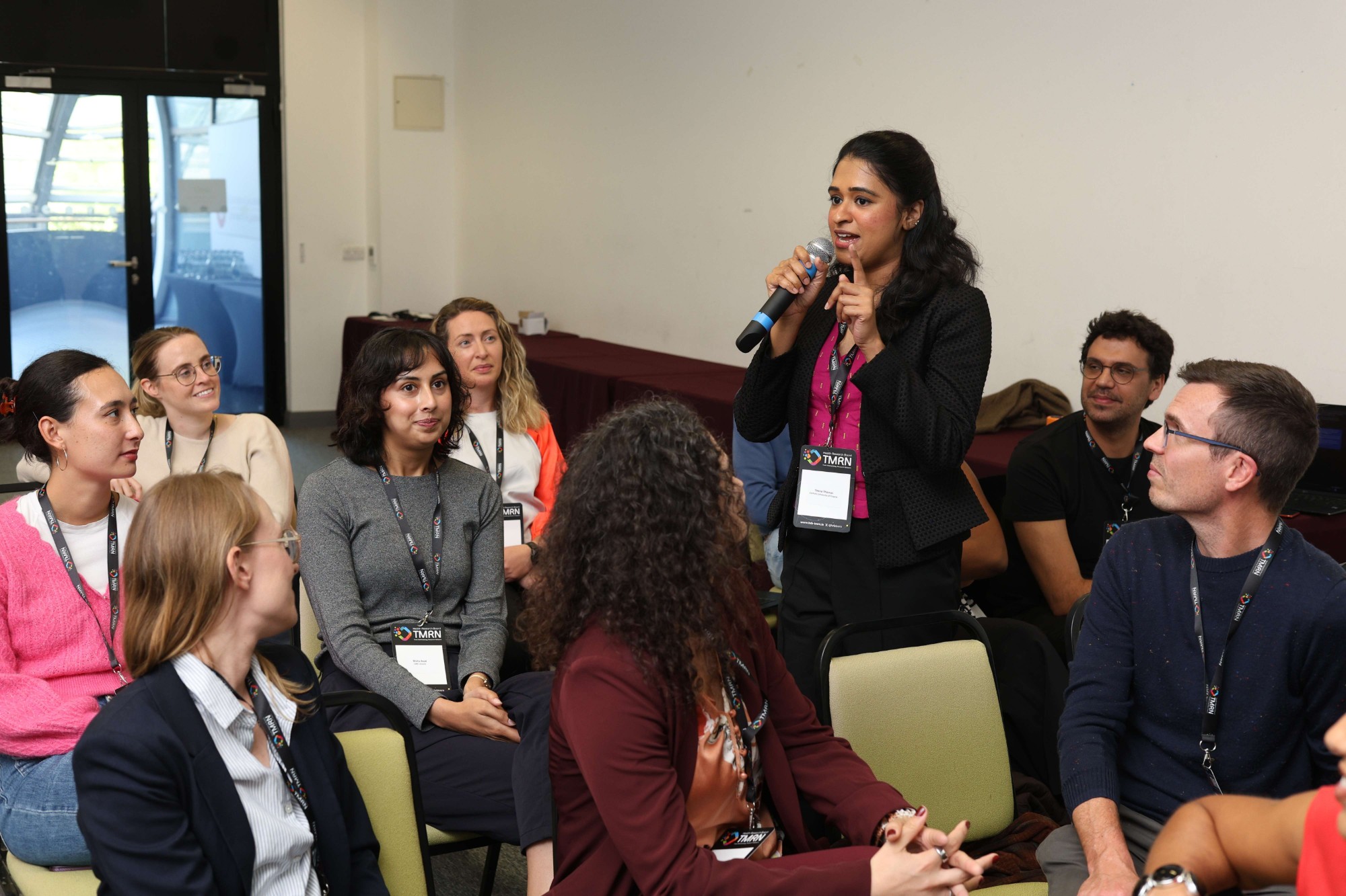 A doctoral candidate speaking into a microphone during a group discussion